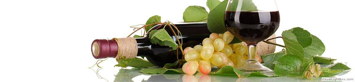 Скинали — Бокал красного вина, бутылка и виноград лежат на столе